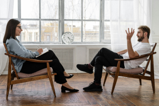 Two people sitting in front of each other while one takes notes.