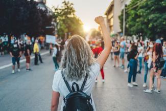 Woman raising her fist in the air at gathering in street.