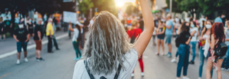 Woman raising her fist in the air at gathering in street.
