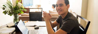 Teenager smiling in front of laptop.