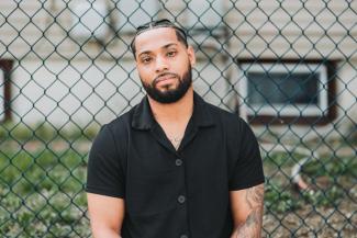 Man sitting in front of a fence.