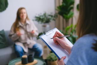 Therapist with patient writing on clipboard
